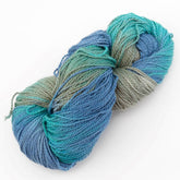 A hank of Great Adirondack Organic DK Cotton yarn in shades of blue, green, and gray is coiled neatly against a plain white background. The yarn from Great Adirondack Yarn Co, Inc. appears soft and thick, suitable for knitting or crocheting.