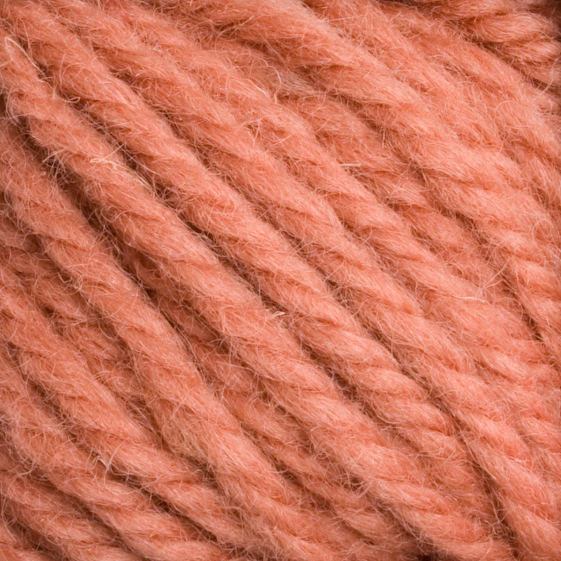 Close-up view of Halcyon Yarn Classic Rug Wool | Strand by Caledonian Dye Works in a dusty rose color. The thick, soft yarn strands are loosely twisted, exhibiting a fuzzy texture perfect for rug weavers. Hand-dyed for a unique touch, this classic rug wool infuses charm and warmth into any project.