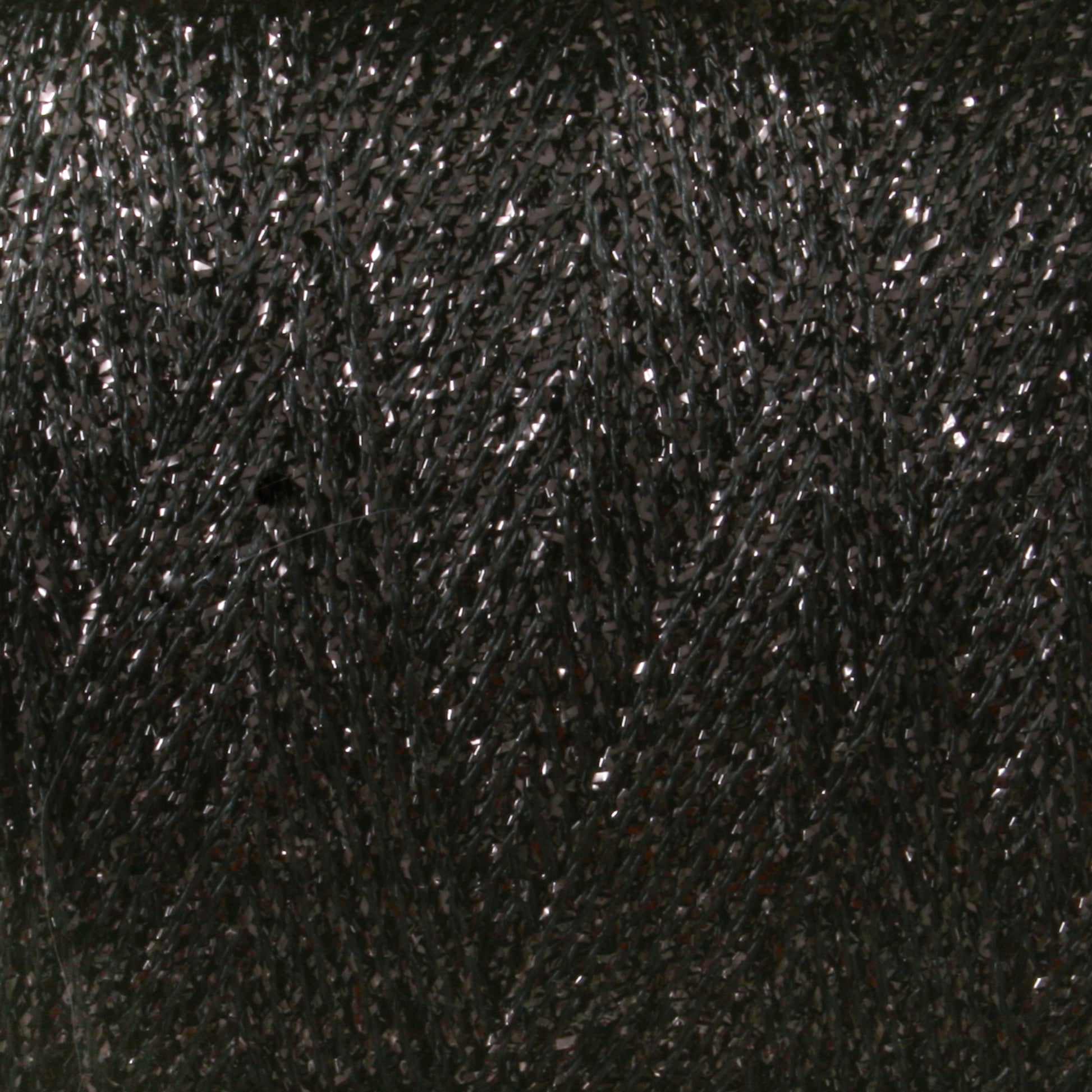 Close-up image of a spool of shimmering, dark-colored metallic yarn from the Astra Glow Metallic line by Huntingdon Yarn Mill, Inc. The thread has a slight sheen, giving it a sparkly appearance. The texture of the yarn is smooth and tightly wound in a diagonal pattern on this large cone.