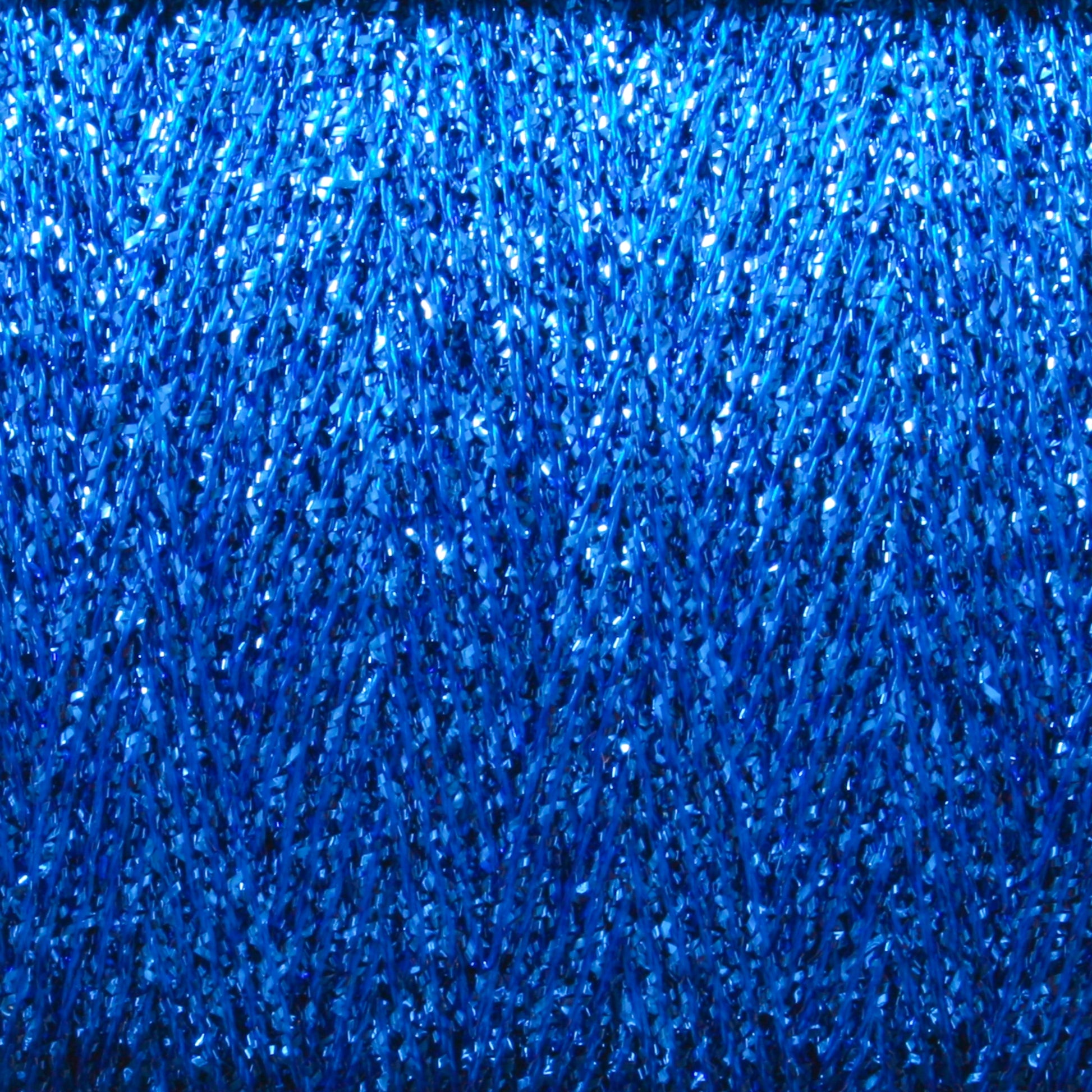 A close-up image of a spool of Astra Glow Metallic | Large Cone from Huntingdon Yarn Mill, Inc. showcases its tightly wound, shiny texture that gives the yarn a glittery appearance. The vibrant blue reflects light for a sparkling effect, making it perfect for projects requiring hand wash care and expert weaving tips.