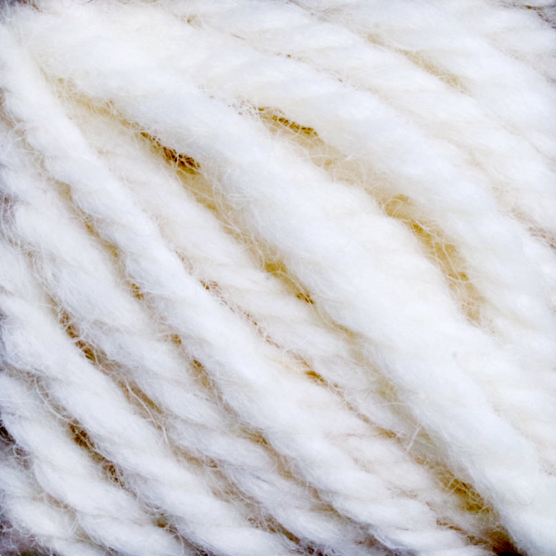 Close-up of a coiled ball of Caledonian Dye Works Halcyon Yarn Classic Rug Wool. The texture is soft and slightly fuzzy, with visible individual strands twisted together to form the yarn. The image highlights the cozy and tactile qualities that appeal to weavers looking for high-quality rug wool skein.