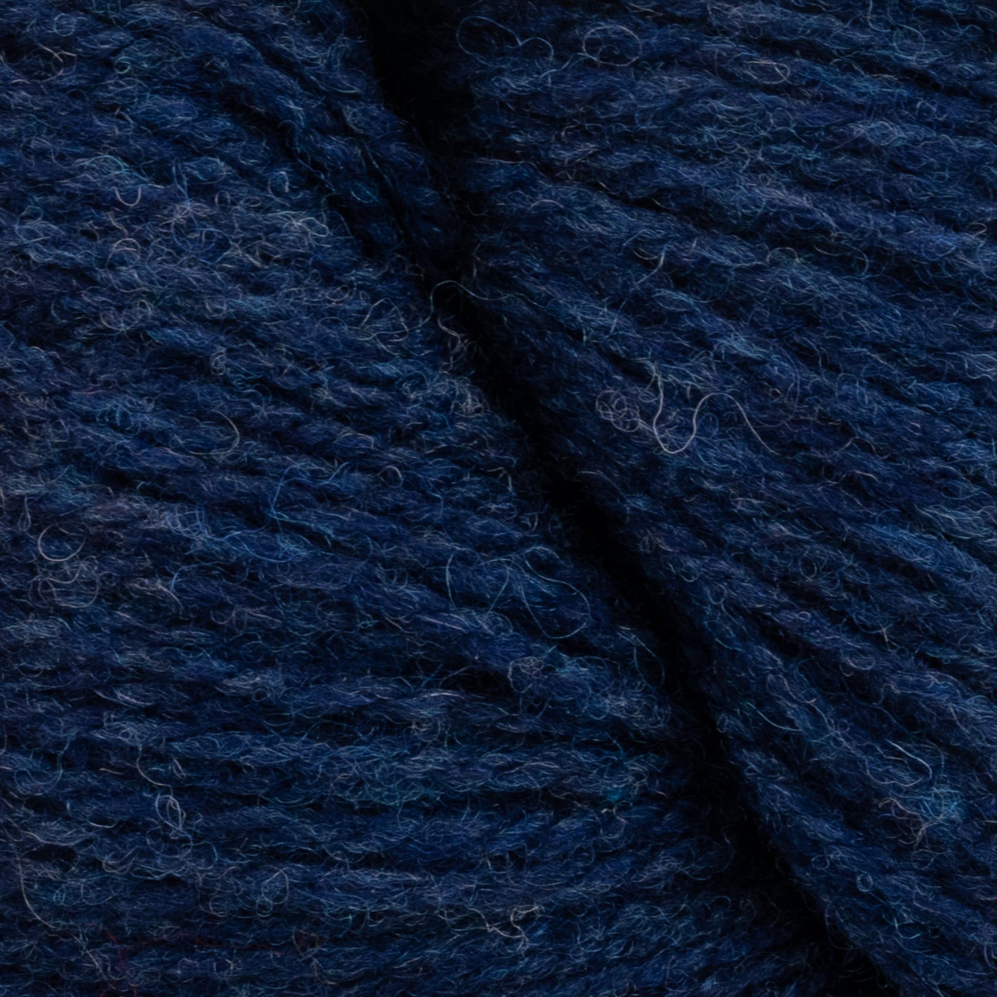 Close-up image of deep blue yarn, showing the texture and fibers intertwined closely together. The Patagonia Organic Merino by Juniper Moon Farm from Knitting Fever / Euro Yarns appears soft and slightly fuzzy, with subtle variations in blue shading throughout.