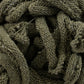 Close-up image of a tangled mass of green knitted Harrisville Potholder Loops - Traditional Size Mini Pack from Friendly Loom, showing a detailed texture with visible stitches and loose fibers. The material appears soft and slightly fuzzy, resembling the intricate weaving patterns created on a traditional loom, with a mix of tightly and loosely woven sections.