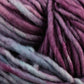 Close-up of thick, soft Malabrigo Mecha wool yarn with a blend of colors, including shades of purple, pink, and blue, creating a rich and textured appearance. This Malabrigo Yarn superwash bulky yarn is slightly twisted, giving the kettle dyed strands a fluffy and cozy look.