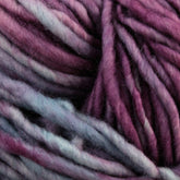 Close-up of thick, soft Malabrigo Mecha wool yarn with a blend of colors, including shades of purple, pink, and blue, creating a rich and textured appearance. This Malabrigo Yarn superwash bulky yarn is slightly twisted, giving the kettle dyed strands a fluffy and cozy look.