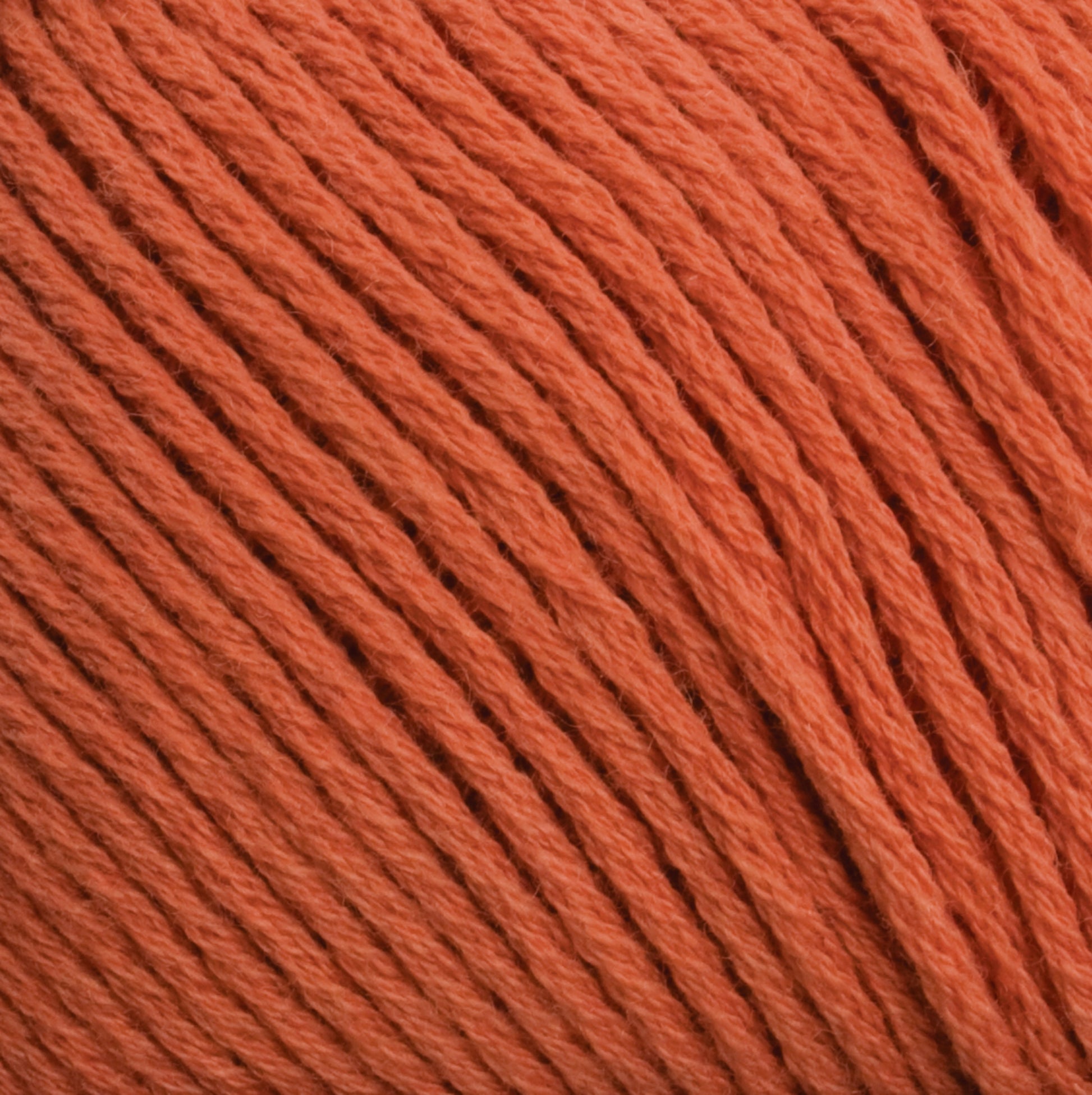 Close-up image of an orange yarn ball, showing detailed texture and tightly wound strands. The Cotton Fleece by Brown Sheep has a smooth, consistent appearance and the color is a vibrant, rich orange—perfect for intricate knitting patterns.