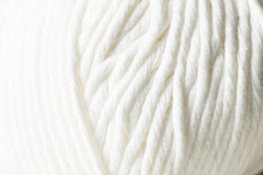 A close-up image of the Jo Sharp Desert Garden Aran Cotton from Kingfisher Yarn & Fibre highlights the soft, white yarn, revealing the texture and twists of its fibers. The thick, fluffy yarn suggests it is an Aran weight cotton suitable for knitting or crocheting warm, cozy items. The background is entirely filled with the yarn, emphasizing its texture and knitting performance.