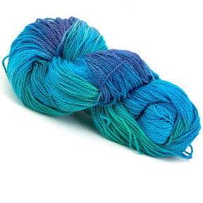 A skein of Great Adirondack Organic DK Cotton from the Great Adirondack Yarn Co, Inc., hand-dyed in multicolored shades of blue and teal, loosely wound into a coil on a white background. The yarn appears soft and textured, making it ideal for knitting or crocheting projects.