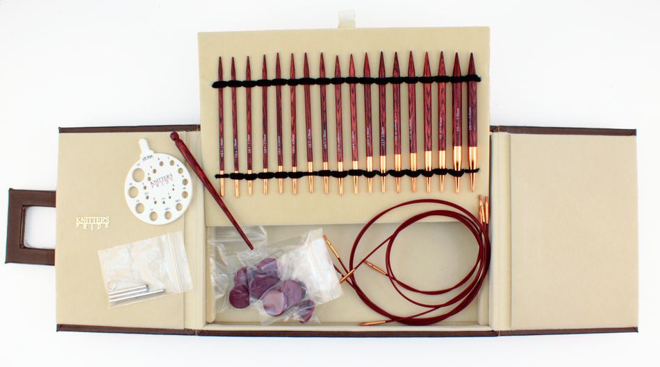 The Symfonie Rose Interchangeable Circular Knitting Needle Set by Accessories Unlimited includes maroon, interchangeable knitting needle tips made from rosewood laminated birchwood, cable connectors, a circular needle size gauge, plastic caps, a key, a fabric pouch, and various accessories—all neatly organized in a beige case.