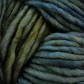 Close-up of thick, multicolored Malabrigo Mecha yarn twisted together. This kettle-dyed yarn from Malabrigo Yarn features shades of green, blue, and brown, creating a natural, earthy blend of colors. The soft and slightly fuzzy texture suggests it is meant for knitting or crocheting.