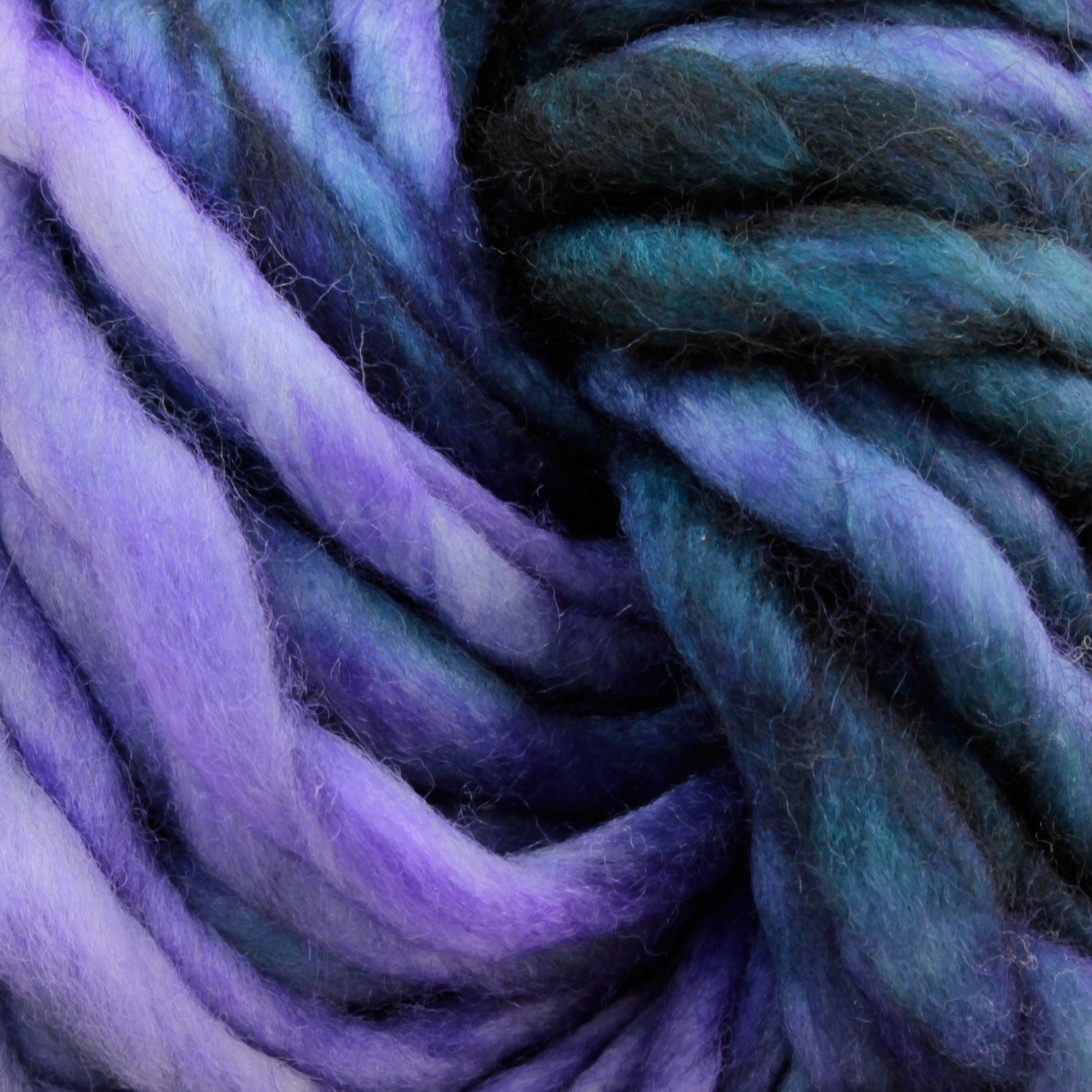 Close-up of Malabrigo Rasta yarn by Malabrigo Yarn, showcasing super bulky, multicolored strands in shades of purple, blue, and green. The texture appears soft and fluffy, making it ideal for quick-to-knit projects or crocheting endeavors.