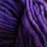 Close-up image of thick, soft Malabrigo Mecha yarn in various shades of purple, from dark to light. The superwash bulky yarn appears fluffy and tightly wound, creating a textured and cozy appearance with its beautiful kettle-dyed hues.