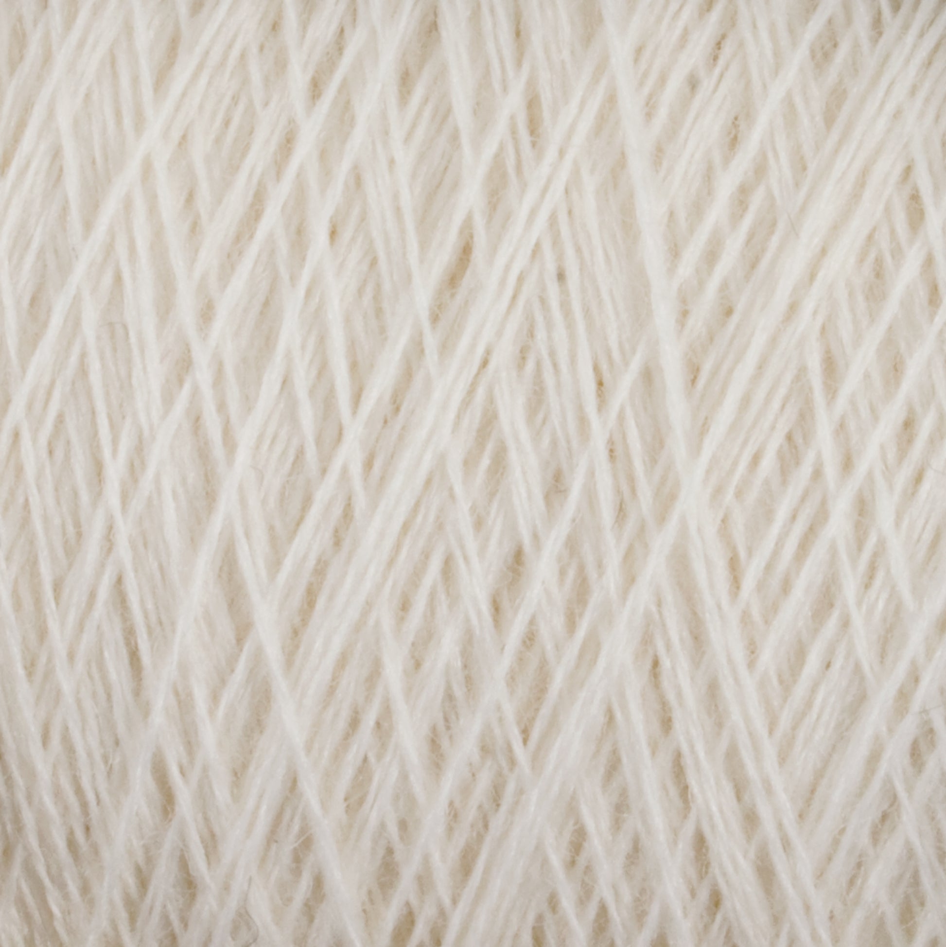 A close-up view of a bundle of cream-colored JaggerSpun Maine Line 3/8 Yarns from Jagger Brothers, Inc., showcasing the detailed texture and intricately neat fibers wound together. The strands form a soft and uniform pattern of worsted spun yarns on the large cone.