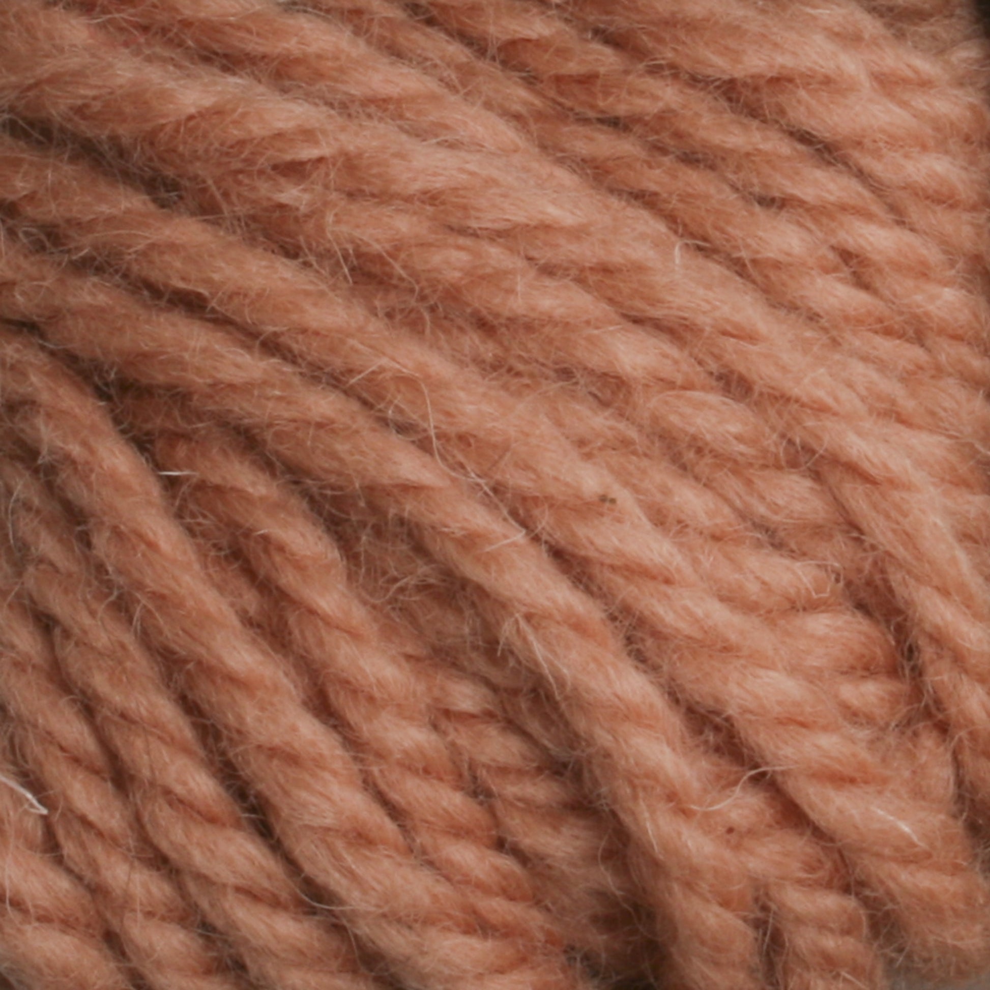 Close-up image of soft, chunky Halcyon Yarn Classic Rug Wool from Caledonian Dye Works in a light salmon pink color. The twisted strands showcase the texture and thickness of the yarn, making it appear suitable for cozy knit or crochet projects—a perfect choice for rug weavers seeking high-quality wool.