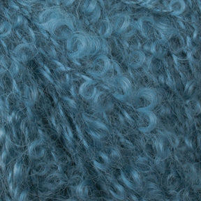 Close-up view of tight, curly, blue fibers with a soft, fuzzy texture. The dense arrangement of curls creates a rich, intricate pattern reminiscent of Caledonian Dye Works’ Victorian Bouclé Mohair Yarn from their Signature Collection.