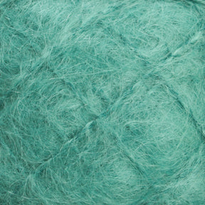 Close-up of the Victorian Brushed Mohair Yarn in a large skein from Caledonian Dye Works. The teal-colored fibers are tangled, fluffy, and wispy, creating a soft-looking, intricate pattern. The luxurious mohair boasts a rich and vibrant teal hue that gives it both a soothing and lively appearance.