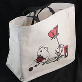 The Mouse Project Tote by Mum n Sun Ink, from the brand Bonnie Bishoff, is a white Envirotote canvas tote bag with black handles. It features a printed design of a white mouse holding a red and black object, positioned next to a red flower and a small red rectangular object. Perfect for carrying shawl pins, the bag is set against a black background.