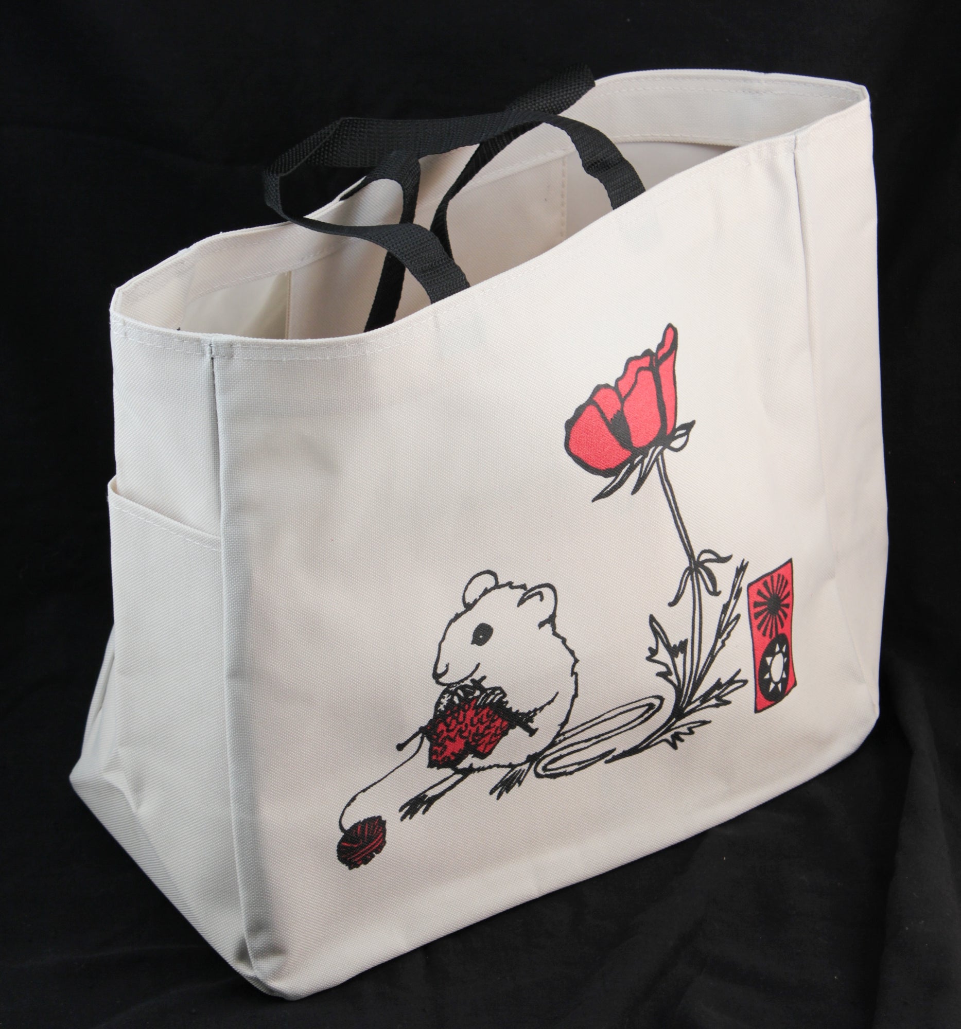 The Mouse Project Tote by Mum n Sun Ink, from the brand Bonnie Bishoff, is a white Envirotote canvas tote bag with black handles. It features a printed design of a white mouse holding a red and black object, positioned next to a red flower and a small red rectangular object. Perfect for carrying shawl pins, the bag is set against a black background.