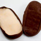 A pair of Bryson Distributing, Inc.'s suede leather and fleece soles is shown, one facing up and the other facing down. The bottom of the slippers appears to be cushioned with suede soles, while the inside lining is light-colored fleece, likely providing comfort and warmth.