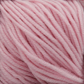 Close-up image of Plymouth Yarn Co.'s Plymouth Select Worsted Merino Superwash in soft pastel pink. The thick, closely wound strands highlight a smooth and fluffy texture with excellent stitch definition. The delicate and gentle appearance of the yarn makes it perfect for knitting or crocheting cozy garments.