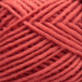 Close-up image of a ball of chunky, coral-colored Lamb's Pride Worsted Yarn by Brown Sheep. The fibers are thick and tightly wound, displaying a soft and slightly fuzzy texture. The color is a warm and muted pinkish-orange, perfect for knitting or crocheting projects as well as felting projects.