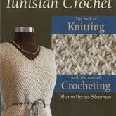 The book "Tunisian Crochet" from National Book Network features a cover with a crocheted sweater displayed on a mannequin, highlighting its high fashion appeal. On the right side, you can see a close-up of the Afghan Stitch pattern. The text reads, "The look of Knitting with the ease of Crocheting.