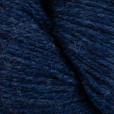 Close-up image of GOTS certified Patagonia Organic Merino yarn in dark blue by Juniper Moon Farm, offered by Knitting Fever / Euro Yarns. The detailed texture and fibers are visible, showing the yarn's fluffy and densely wound structure. Subtle variations in the blue hues give it a rich and vibrant appearance.