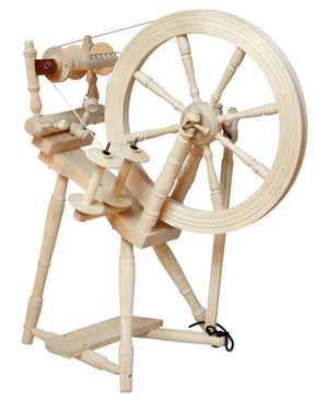 The Kromski North America Prelude Spinning Wheel features a large wooden wheel connected to several smaller components and spools. The intricately crafted spinning wheel rests on a sturdy base with finely turned legs and supports, showcasing traditional craftsmanship in European alder and birch.