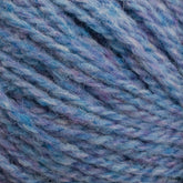 Close-up of a ball of Harrisville Designs' Harrisville Highland - Cones yarn in mixed shades of blue, with hints of purple. The image showcases the detailed texture of the unscoured fibers, highlighting the soft and thick appearance enhanced by spinning oils.