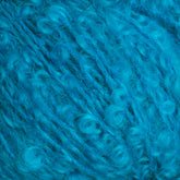 A close-up image showcases the vibrant, bright blue Victorian Bouclé Mohair Yarn from Caledonian Dye Works. The yarn, textured with twists and curls reminiscent of traditional Mohair Bouclé, has a fluffy and soft appearance. The intricate details of the fibers are prominently visible, highlighting its vibrant color and unique texture.