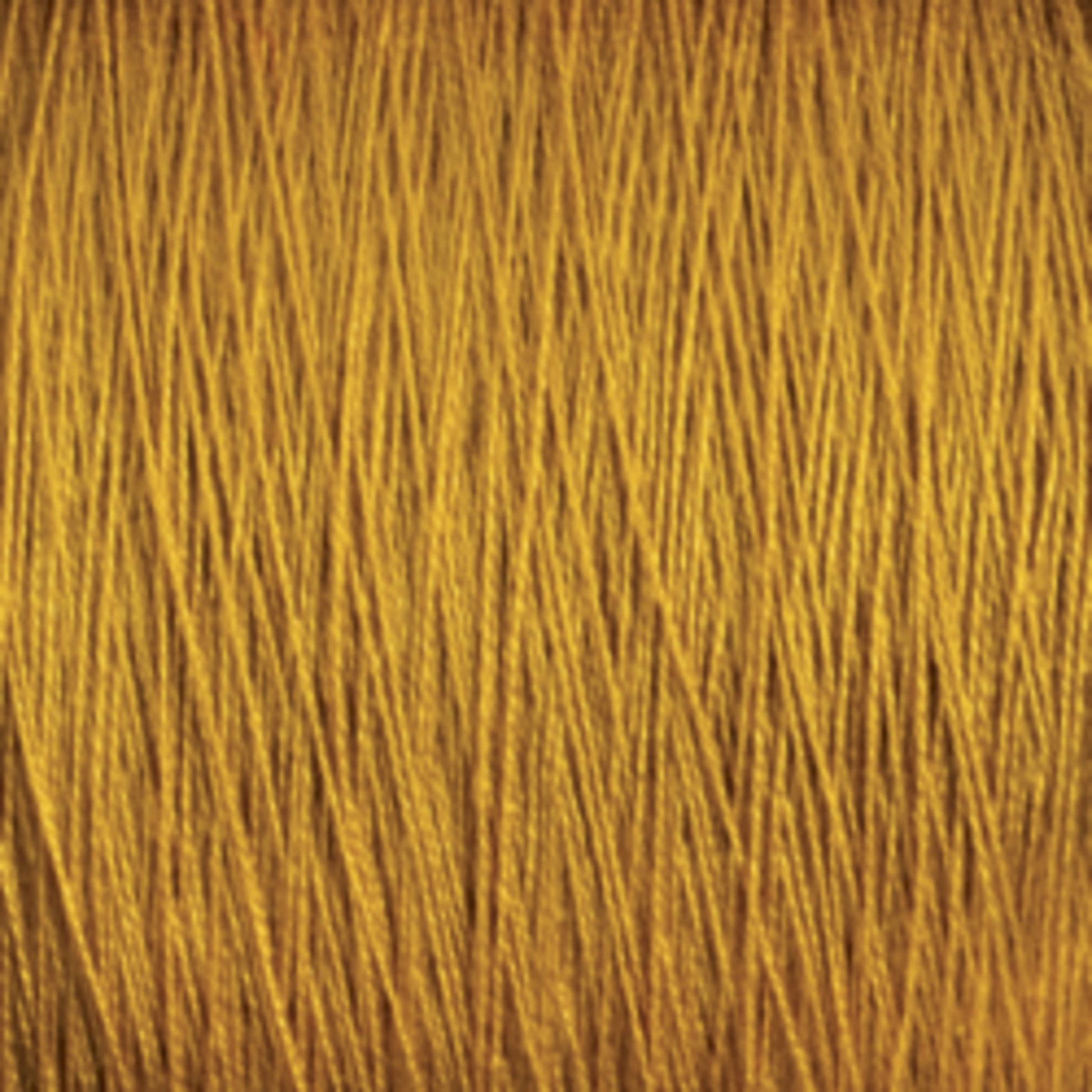 A close-up image of **Supreme Corp.'s** golden-colored **10/2 Pearl Cotton Yarn | Mini-cone**, showing numerous tightly packed strands running parallel to each other. The texture appears smooth and lustrous, with a slight shine reflecting light, highlighting the colorfastness and versatility of this premium yarn.