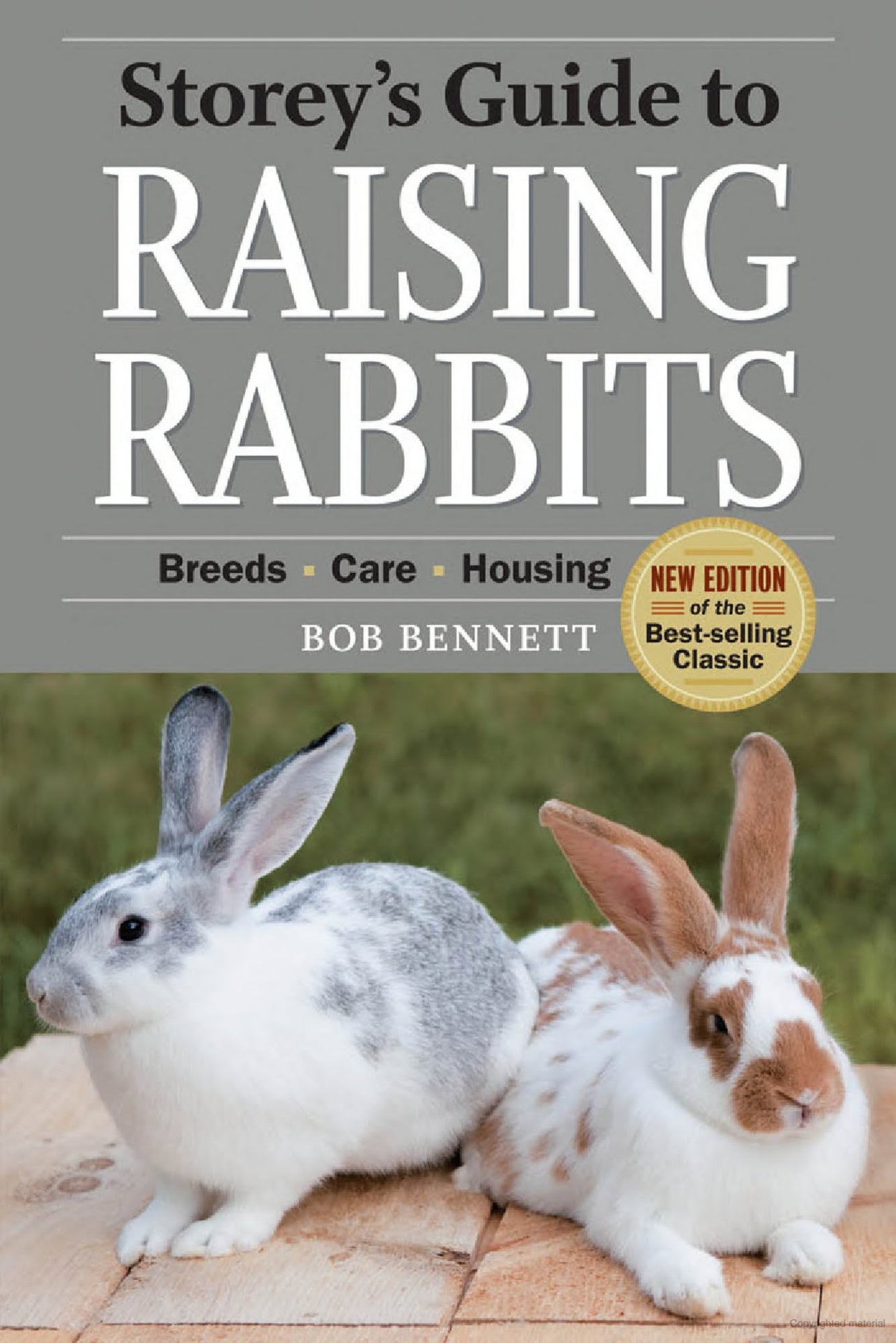 Cover of the book "Storey's Guide to Raising Rabbits: paperback" by Bob Bennett, published by Workman Publishing - Storey. The cover features two rabbits: one white with gray spots and another white with brown spots, sitting on a wooden surface. A gold badge indicates it is a new edition of the best-selling classic on rabbit care and raising rabbits.