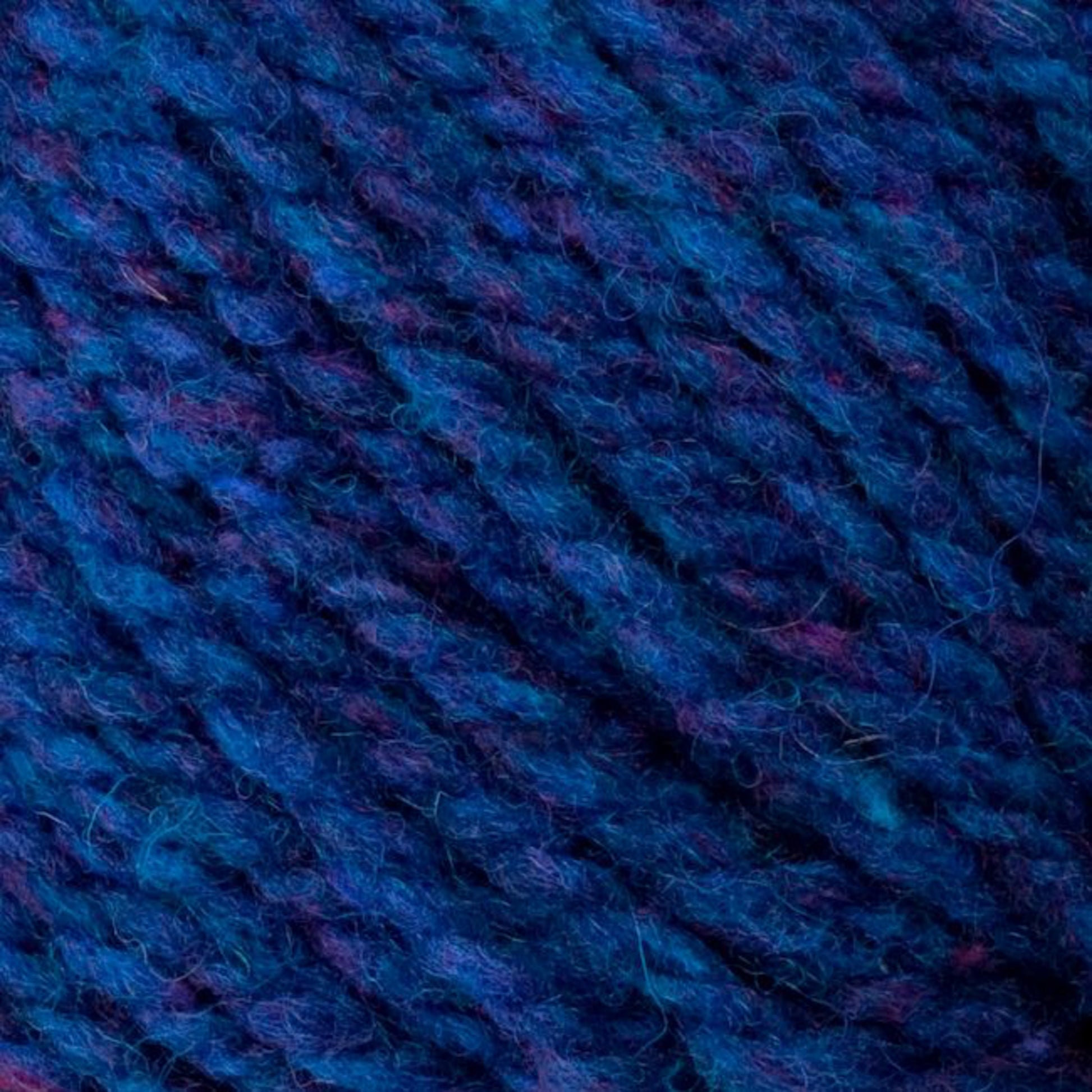 Close-up view of the Bartletts Maine Wool - Sport yarn in blue, featuring subtle hints of purple and pink fibers. The texture appears soft and slightly fuzzy, with interwoven strands creating a dense, tactile surface characteristic of Bartlettyarns.