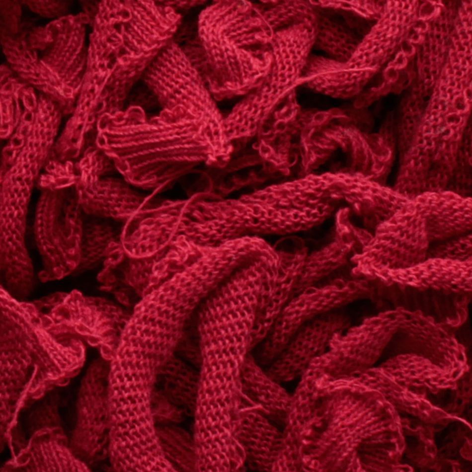 A close-up view of a tangled heap of the red Harrisville Potholder Loops - Traditional Size Mini Pack by Friendly Loom, showing various loops and intricate textures reminiscent of a traditional loom. The yarn appears soft and thick, intertwining in a complex pattern.