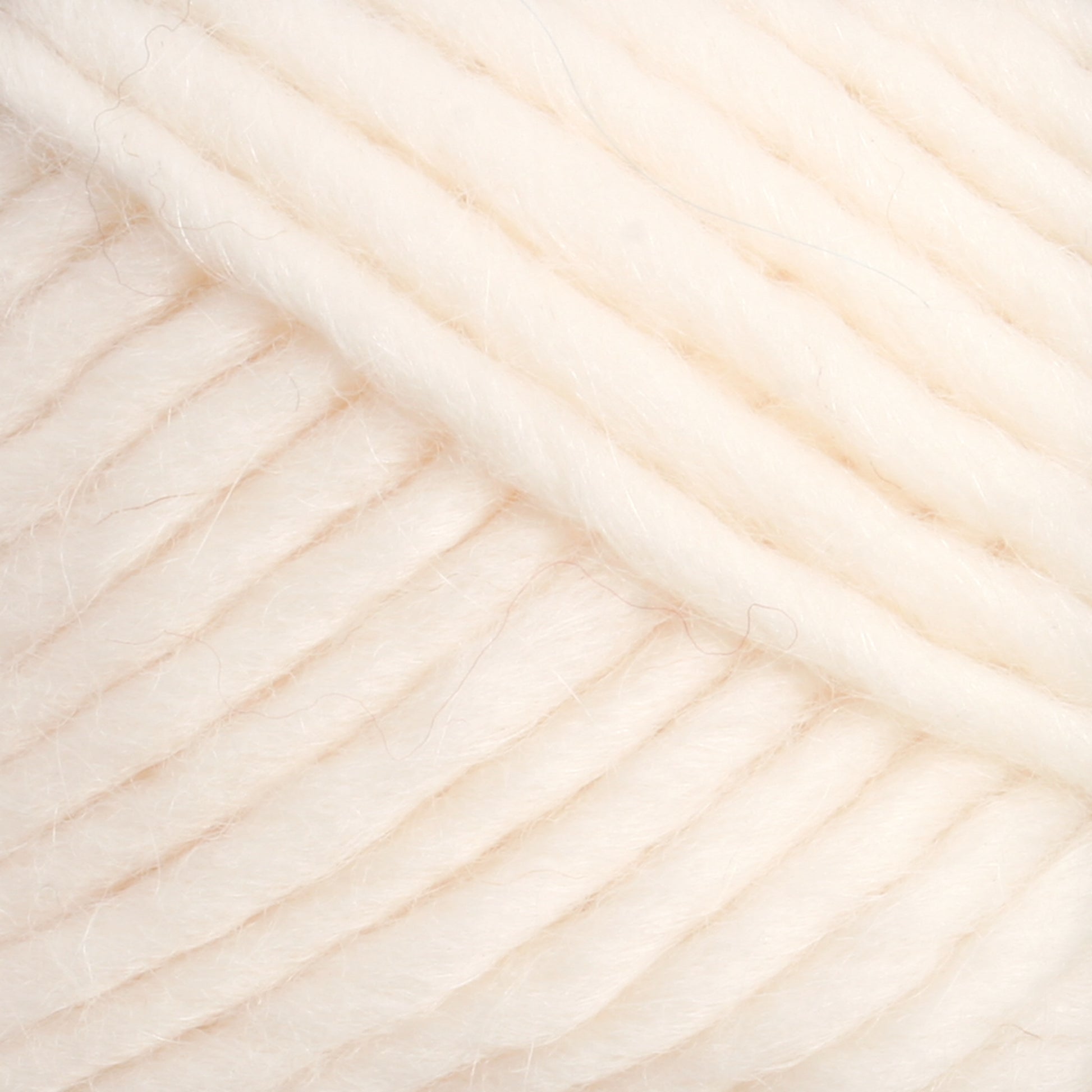 Close-up of Lamb's Pride Worsted Yarn by Brown Sheep, showcasing its cream-colored, chunky wool with a soft, fuzzy texture and thick strands coiled together. Ideal for felting projects or Navajo-style weaving, the yarn is tightly wound with each strand clearly visible, highlighting the natural fibers and slight variations in thickness.