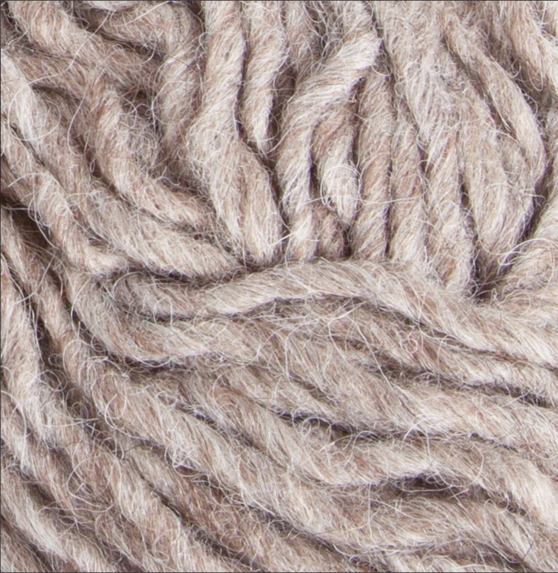 Close-up view of Berroco, Inc.'s Jöklalopi (Bulky Lopi) yarn twisted into thick, textured strands. The yarn has a soft and slightly fuzzy appearance, evoking a rustic handmade charm, suitable for knitting or crocheting chunky winter sweaters.