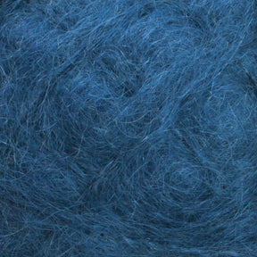 A close-up image of the Victorian Brushed Mohair Yarn in blue from Caledonian Dye Works showcases a tangled and textured appearance, resembling a mixture of wool and luxurious mohair fibers. The fibers are intertwined, forming a dense, somewhat chaotic pattern with visible strands in varying shades of blue.