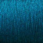 A close-up image of teal-colored 10/2 Pearl Cotton Yarn | Mini-cone from Supreme Corp. tightly wound into a ball. The texture of this versatile yarn is clearly visible, showcasing its soft, fibrous strands and impressive colorfastness.