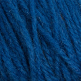 Close-up of Halcyon Deco Rug Wool by Caledonian Dye Works, showing detailed textures and fibers. This 100% wool yarn appears thick and plush, with a rich, deep blue hue. The fibers intertwine smoothly, highlighting the twist and weave of this versatile yarn's strands.