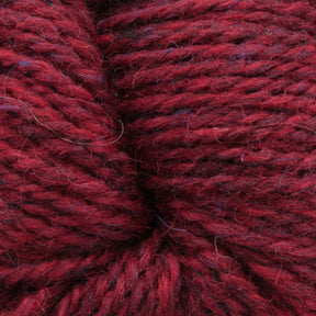 Close-up image of soft, thick Peace Fleece Yarn by Harrisville Designs with subtle maroon and dark purple hues. The individual strands, crafted from a wool and mohair blend, are visibly intertwined, creating a textured and cozy appearance, ideal for worsted weight knitting or crocheting projects.