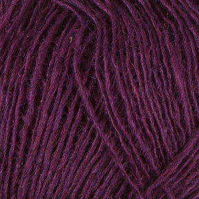 Close-up of a rich, deep purple yarn from the Einband Lopi collection by Berroco, Inc. The texture highlights the intertwined fibers, with some strands appearing slightly fuzzy. Made from Icelandic wool, the yarn is neatly wound, showcasing the intricacies and variations in both color and thickness.