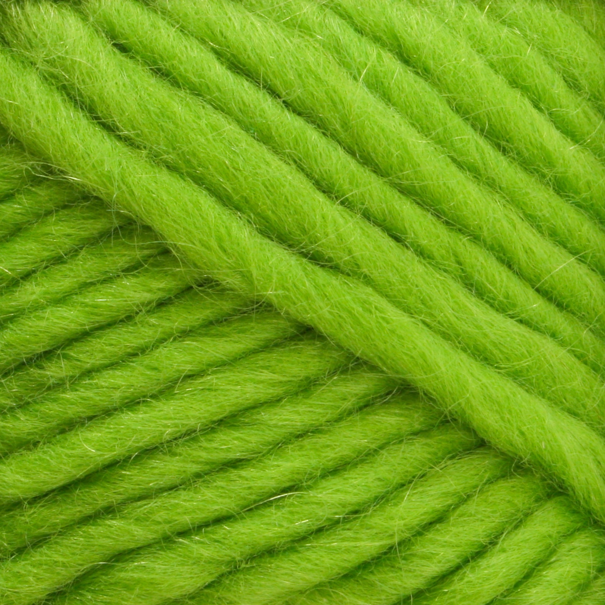 Close-up of a ball of Lamb's Pride Bulky Yarn by Brown Sheep in a vibrant green hue. The yarn appears thick and fuzzy, with visible fibers creating texture. The strands are tightly wound next to each other, displaying a rich and vibrant color ideal for knitters and crocheters crafting cozy projects.