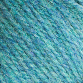 Close-up of Bartlettyarns Maine Wool Yarn in blue, showcasing its heathered colors with hints of green. The texture is soft and fibrous, blending tightly spun and fluffy strands. This worsted weight yarn from Bartlettyarns reveals the intricate twists and plies in the material.