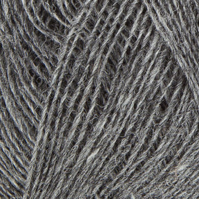 Close-up image of Berroco, Inc.'s Einband Lopi. The texture of the yarn is visibly soft, with strands intertwined in a loose and slightly fuzzy pattern. The color is a uniform grey with minor variations in shades, giving it a natural and organic appearance perfect for delicate lace knitting projects.