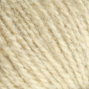 Close-up image of off-white, textured yarn. The medium thickness, worsted weight Bartlettyarns Maine Wool Yarn features visible fibers and a slightly fuzzy surface. The twist of the Bartlettyarns threads is clearly shown, highlighting the soft and cozy texture ideal for knitting or crocheting.