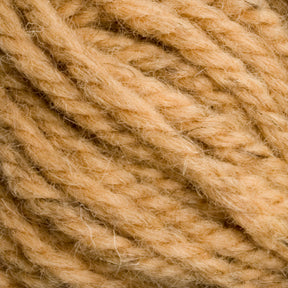 Close-up image of Caledonian Dye Works Halcyon Yarn Classic Rug Wool | Skein in beige. The hand-dyed yarn appears thick, with visible individual threads and fiber texture. The strands are loosely twisted together, showcasing a soft and fuzzy surface that weavers will appreciate. The image focuses on the texture and details of the yarn.
