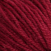 Close-up image of Halcyon Deco Rug Wool in red from Caledonian Dye Works. The fibers are tightly twisted, creating a textured appearance. This 100% wool yarn appears soft and plush, perfect for knitting or crocheting various items. The deep red color is rich and consistent throughout the strands, making it a versatile yarn choice.