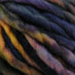 Close-up of colorful, twisted yarns with shades of purple, blue, yellow, and pink intertwined. The fibers appear thick and textured, perfect for quick-to-knit projects using super bulky yarn like Malabrigo Yarn's Malabrigo Rasta.