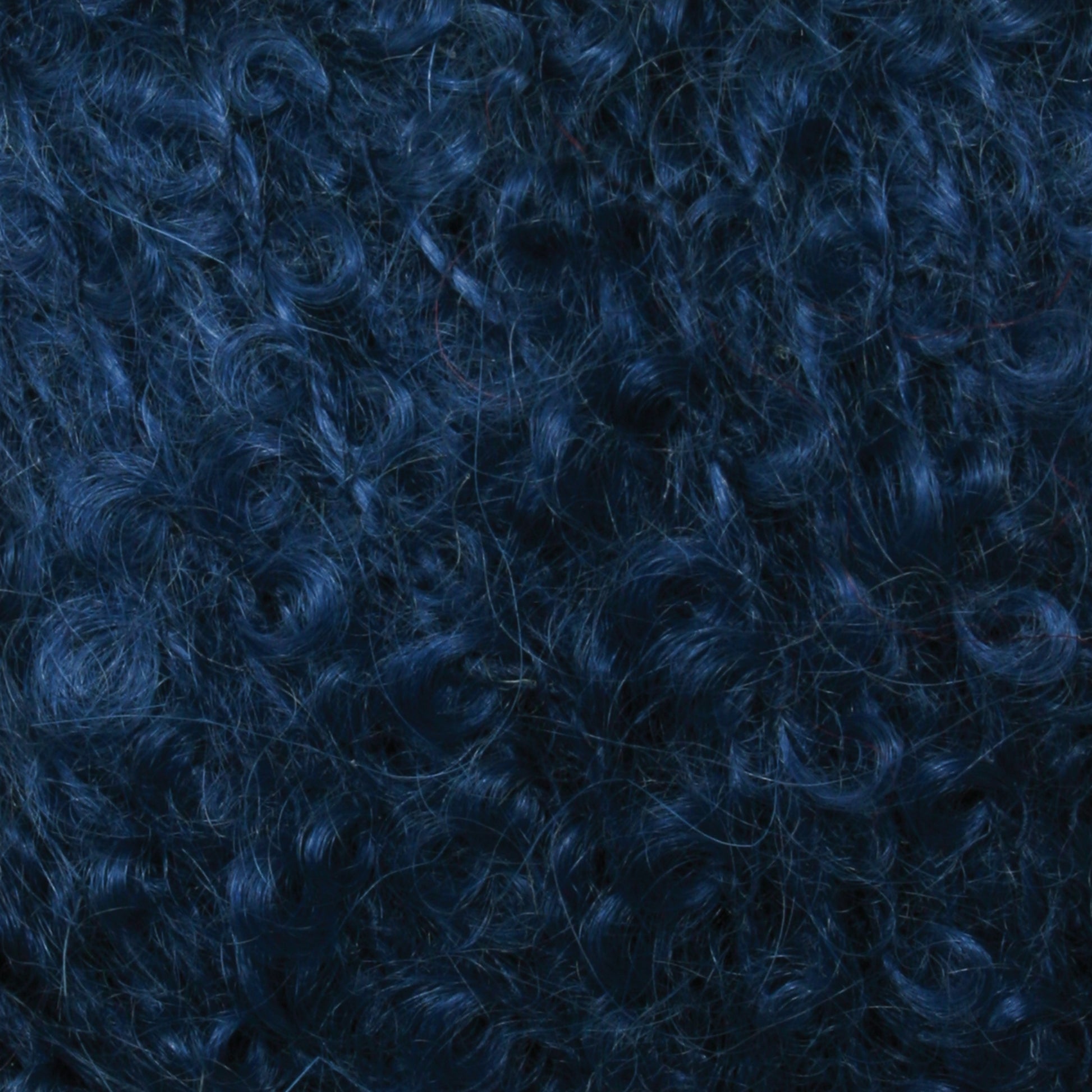 Close-up of dense, dark blue curly hair filling the entire frame. The curls are tight and compact, with a shiny texture that resembles luxurious Victorian Bouclé Mohair Yarn from Caledonian Dye Works. The hair exudes a rich and vibrant appearance.