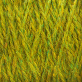 Close-up view of green and yellow Harrisville Designs' Harrisville Highland - Cones yarn fibers woven together, creating a textured pattern. The unscoured yarn appears soft and slightly fuzzy, showing detailed interlocking strands likely treated with spinning oils.